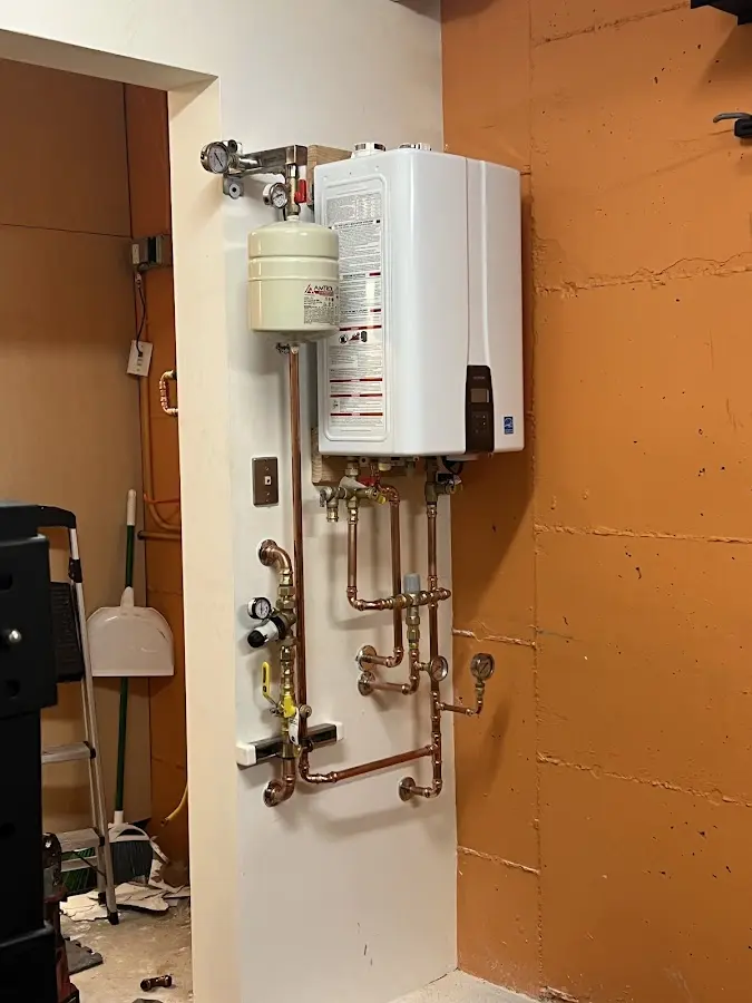 Plumbing technician inspecting water heater connections in Allendale